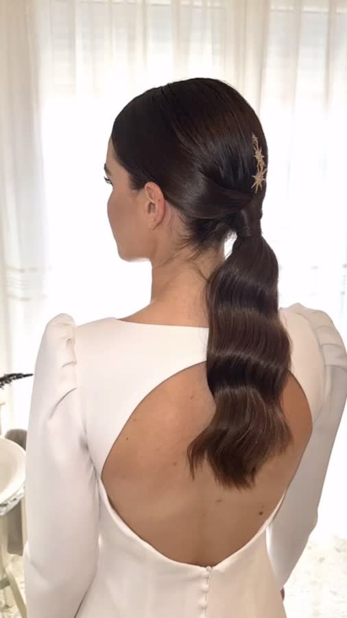 Coleta baja de novia con ondas y horquilla dorada